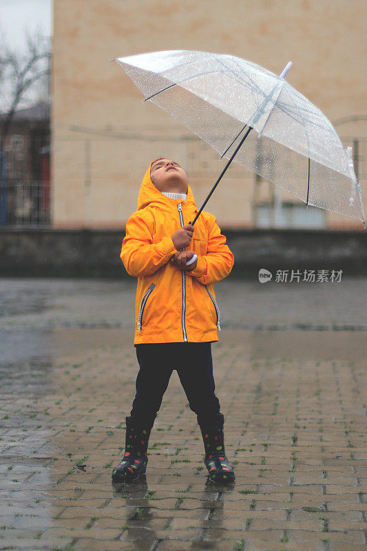 小女孩撑着雨伞在雨中