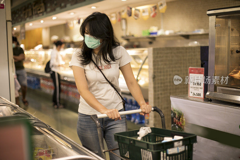 年轻女子在杂货店购物，戴着防护医用口罩