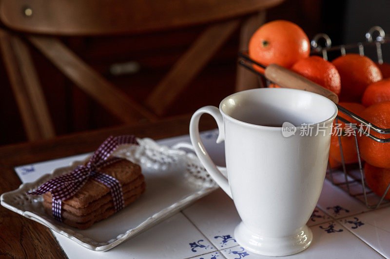 一杯茶，茶壶，饼干和橘子在桌子上-库存照片