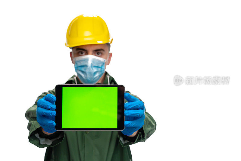 身穿绿色雨衣、头戴安全帽的年轻工程师手持空白屏幕的数字平板电脑