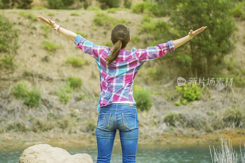 女人的后视图与双臂延伸享受美丽的景色