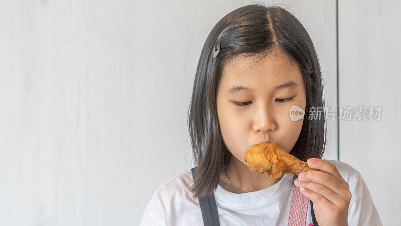 亚洲华人小女孩吃着美味的鸡腿