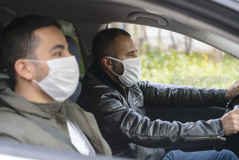 一名男子和他的朋友在城市里戴着防护面具开车