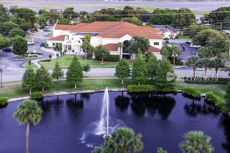 鸟瞰图，绿树成荫的池塘和喷泉在城市的湖滨公园，奥西奥拉县哈特纪念县拥有公共图书馆和Toho湖在基西米市中心，佛罗里达州