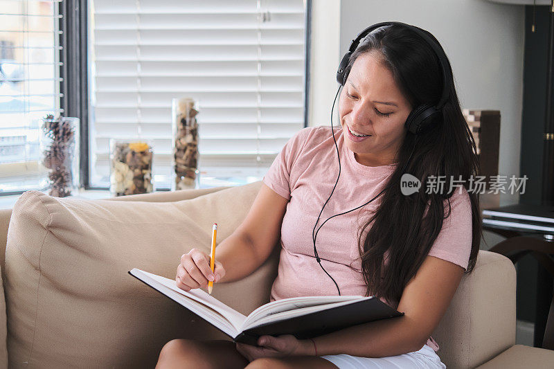 戴着耳机在家工作或学习的拉丁年轻女子