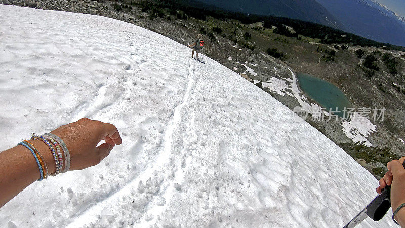 徒步旅行者沿着积雪的山坡跑下去