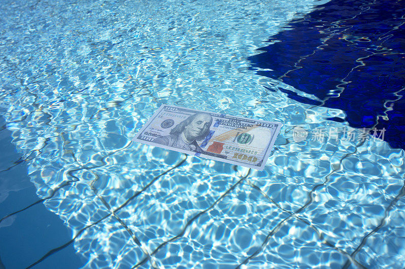 100美元的美钞在湛蓝的水面上游泳