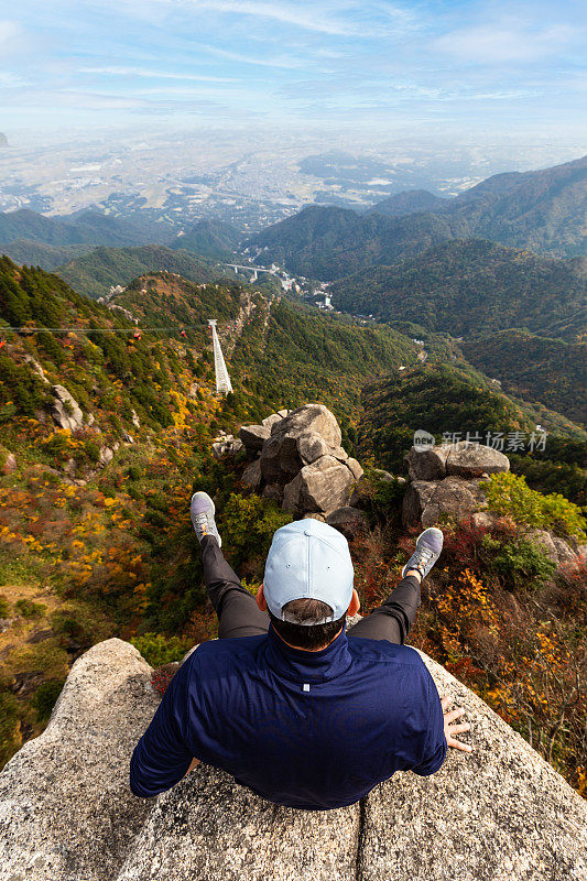 一名男子坐在悬崖边上的山上的秋天山戈寨索