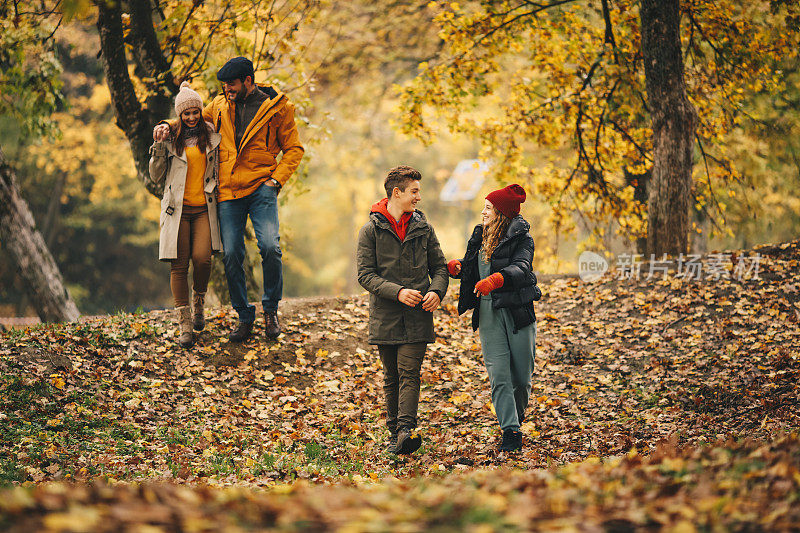 孩子们在森林里玩耍。他们的父母在照顾他们。秋天的季节。