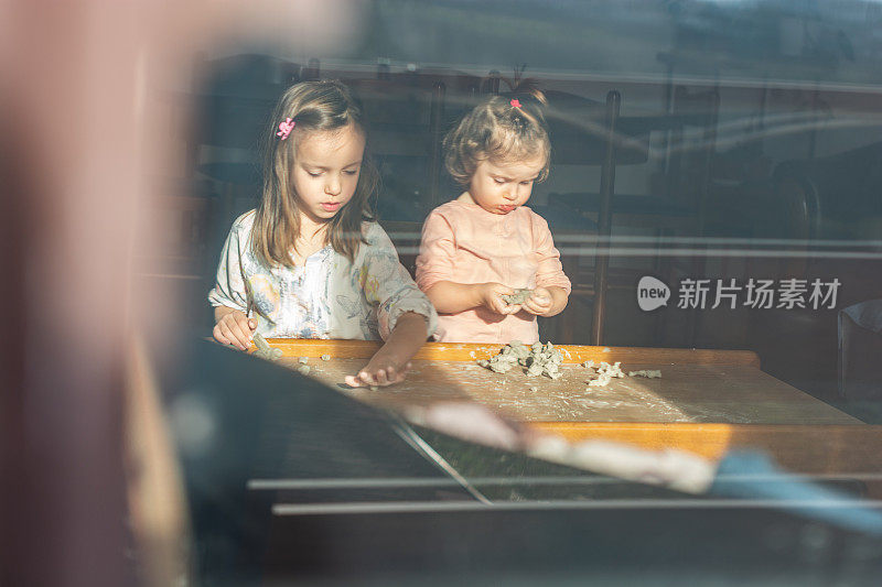 两个女孩在客厅里玩，窗外的景色