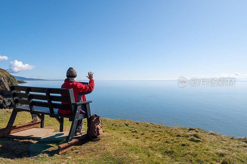 一个退休男子坐在长凳上用着平板电脑