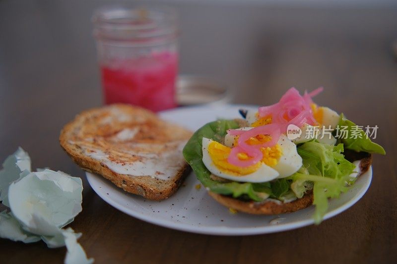 美味的开放式三明治，煮熟的鸡蛋和采摘的粉色洋葱