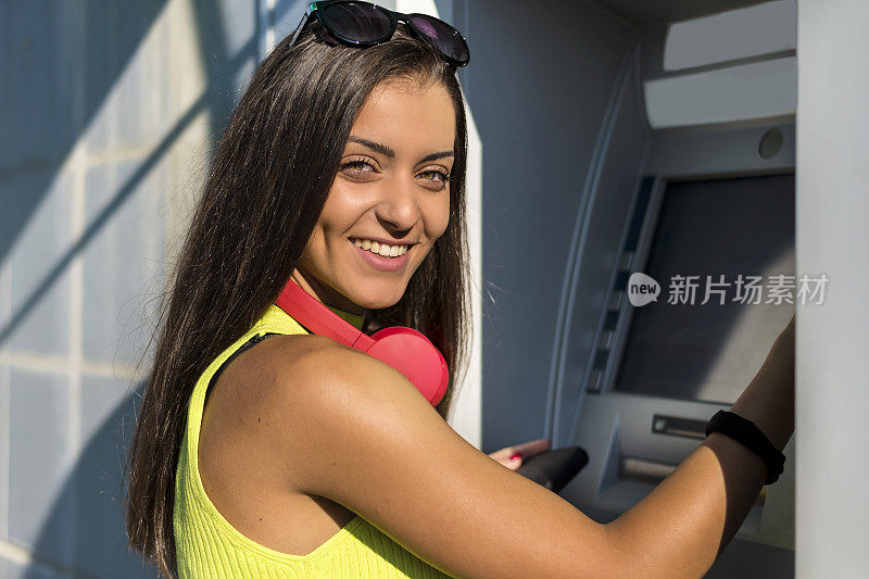 年轻女子在使用自动取款机。