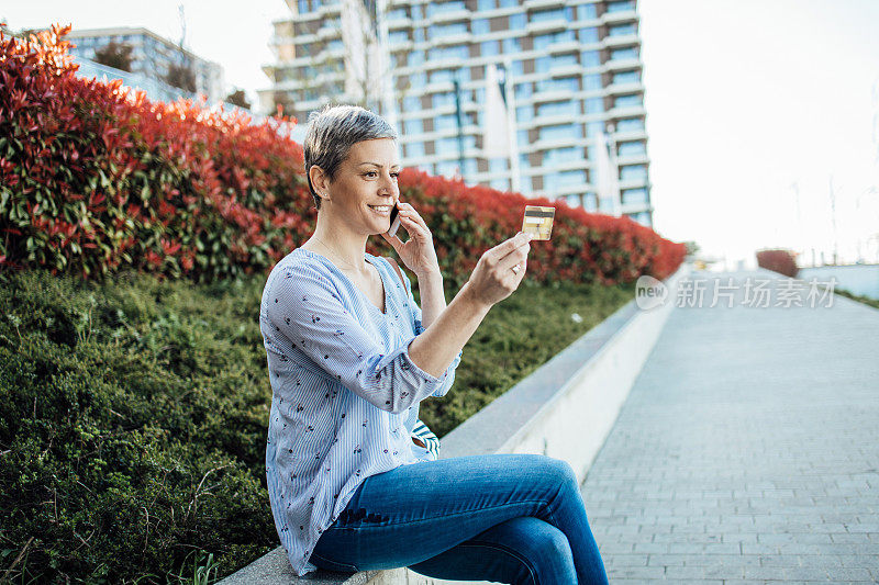 快乐的女人在城里休息用她的信用卡订东西