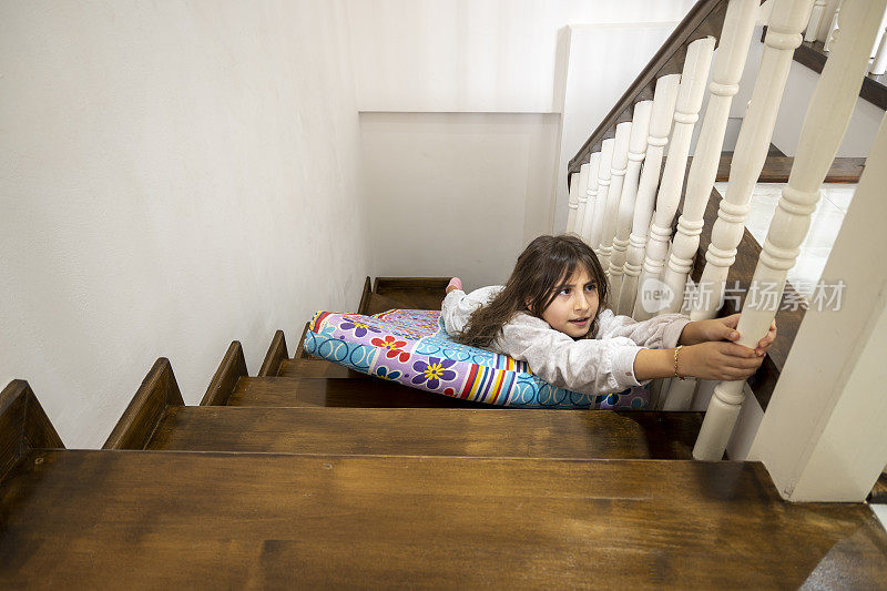 可爱的女孩在家里滑楼梯
