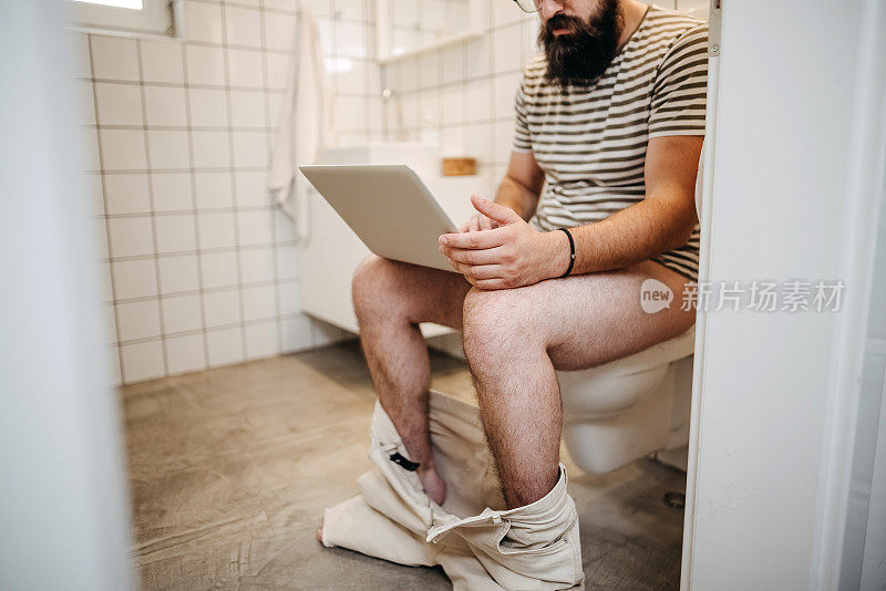 一个年轻人在厕所里用笔记本电脑
