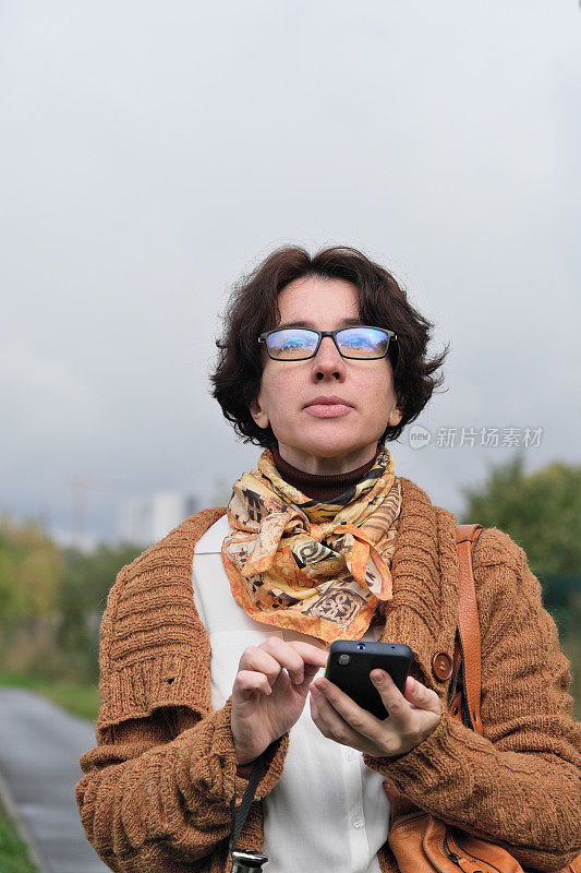 成熟的女人在城市的大街上等车