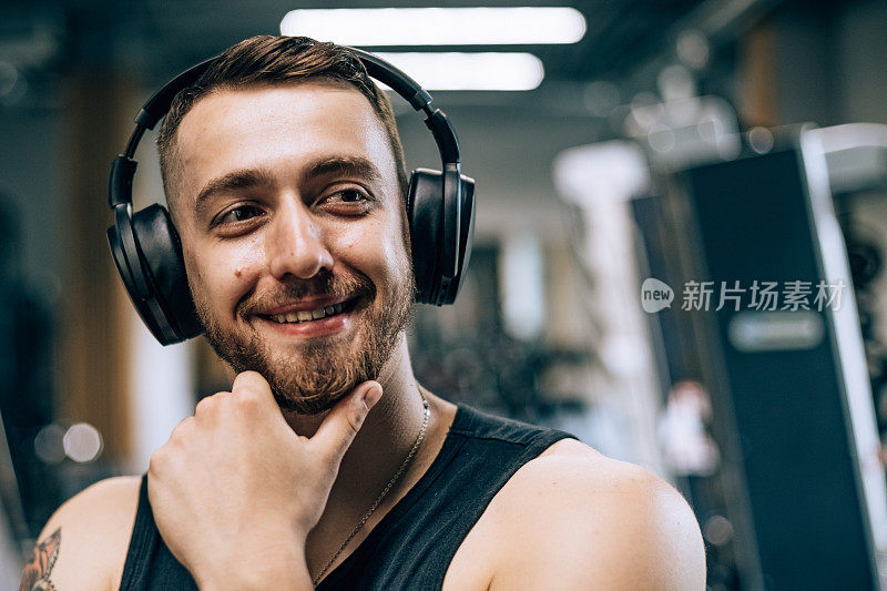 一名男子在健身俱乐部进行运动训练时，正在使用无线耳机听音乐和收听录音。男人在健身房，人们在室内的生活方式。
