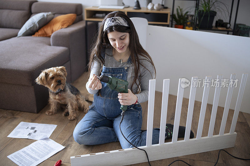 年轻的母亲和她的小猎犬在整理婴儿床。