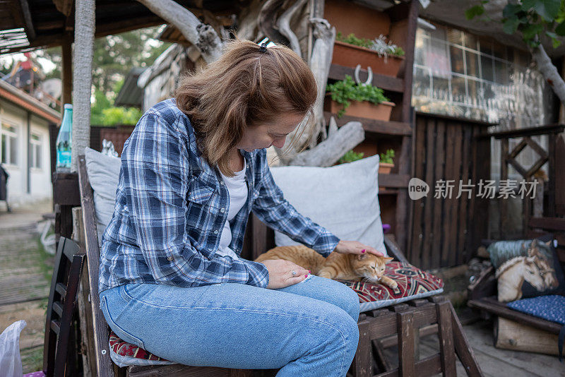 一个女人在花园的沙发上抚摸她的猫