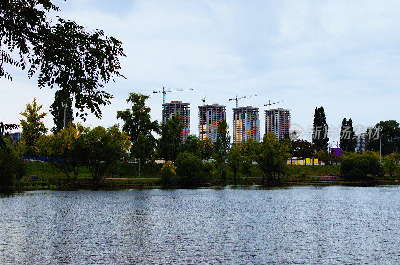 乌克兰基辅，特尔宾湖风景如画。四座在建高层建筑，城镇起重机映衬蓝天