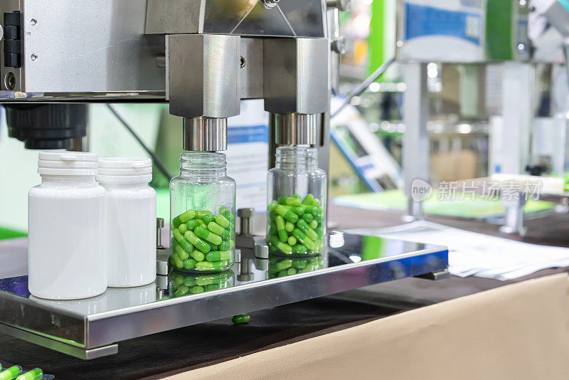 在生产过程中，在自动药胶囊灌装计数机的喷嘴分配器组件下关闭白色透明塑料瓶