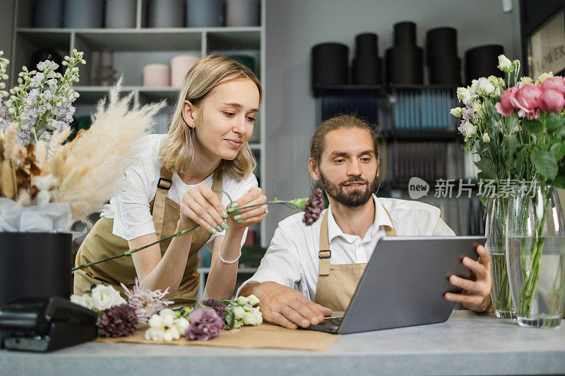 两个工人，男花匠在工作场所的电脑和女帮助他。