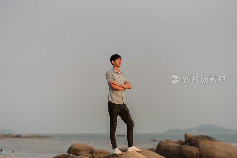 男人站在岩石上欣赏海景