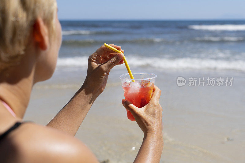 海滩上拿着新鲜饮料的女人