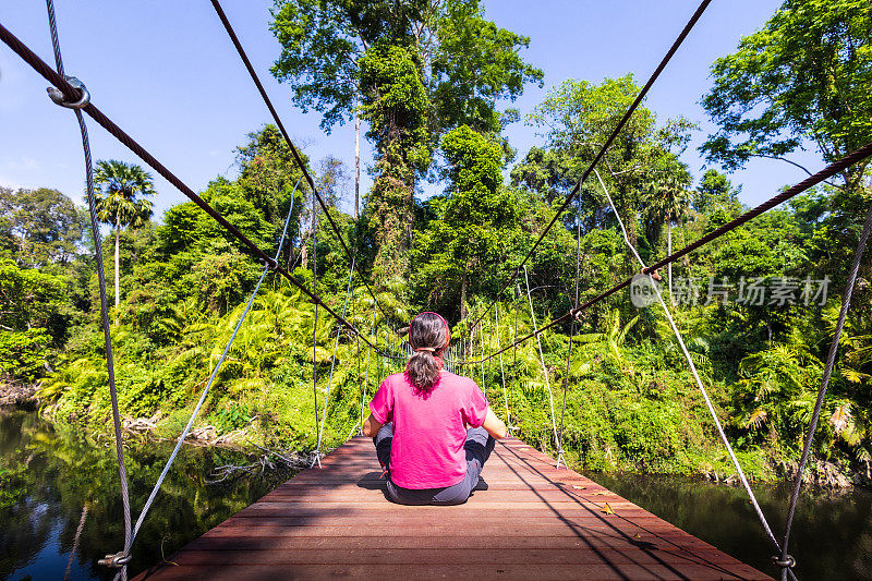 徒步旅行-女人在雨林吊桥上