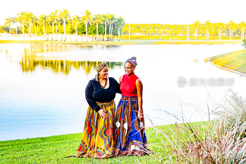 两个女人，母亲和女儿，穿着传统的非洲印花服装，在户外偷拍快乐的肖像来庆祝宽扎节