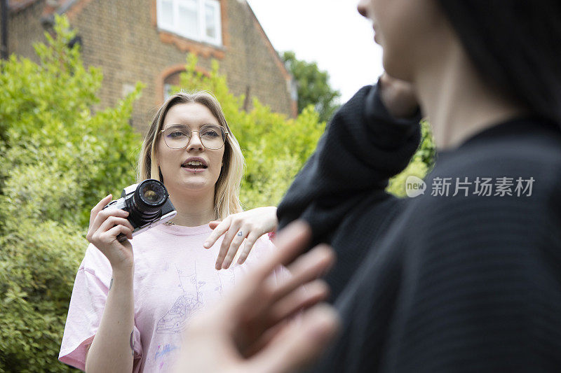 一位年轻的女性正在用相机给她的朋友拍照