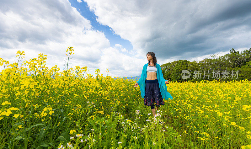 一位妇女在一片黄色的油菜花地里放松和享受户外活动