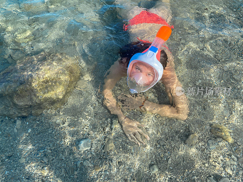 一个十几岁的小女孩在海边戴着潜水面罩
