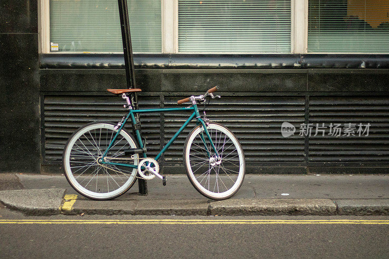 在空荡荡的伦敦街道上，自行车用铁链拴在柱子上