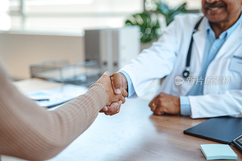 男医生与女病人在诊所工作台上握手的特写
