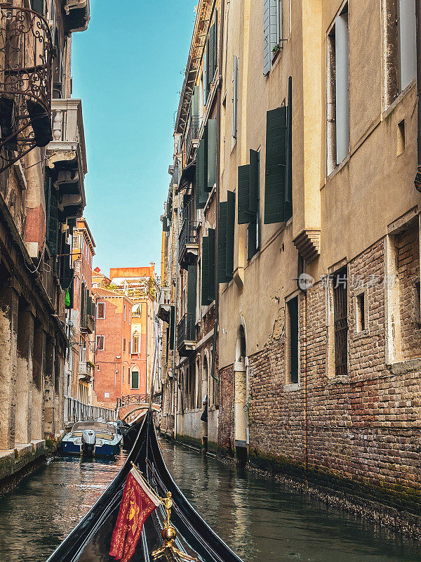贡多拉在意大利威尼斯狭窄的运河中穿梭于房屋之间