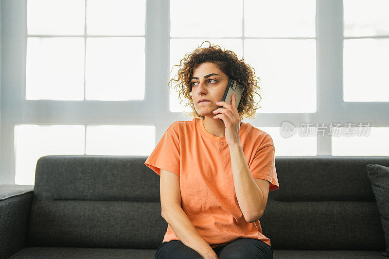 一个体贴的女人坐在客厅的沙发上讲电话