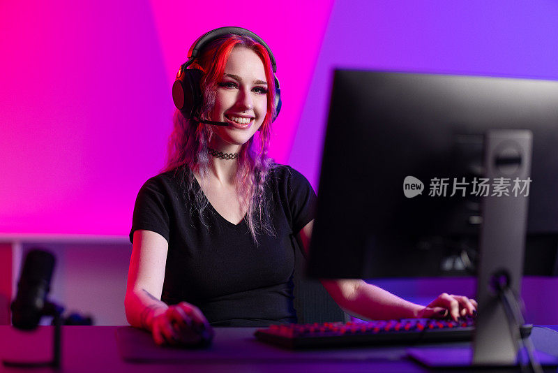 专业微笑的电子竞技玩家女孩在PC上玩在线视频游戏