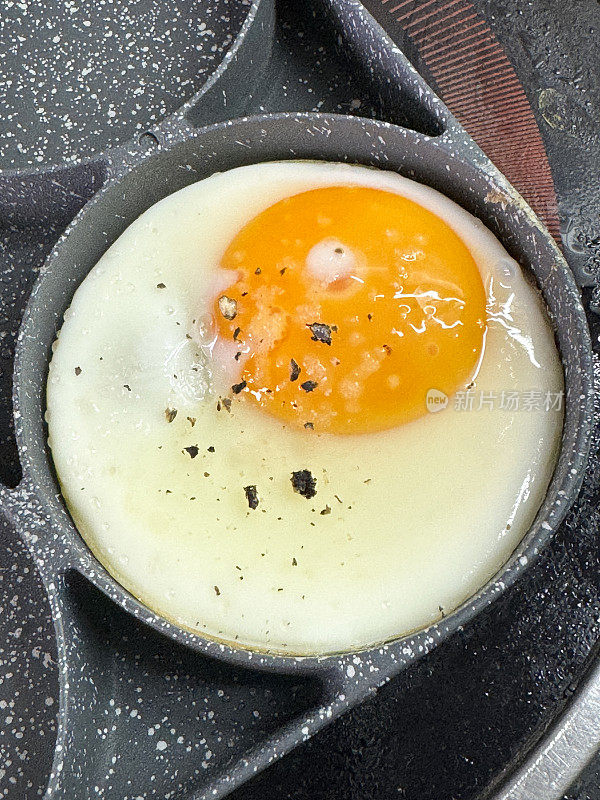 全画幅图像的不粘锅与环煎鸡蛋，鸡蛋正在烹饪锅上的陶瓷滚刀，抬高视图