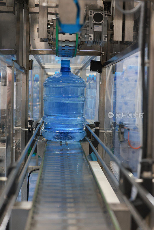 选择性专注于将饮用水装瓶成塑料瓶的工业生产线。输送机在净水生产中的应用。
