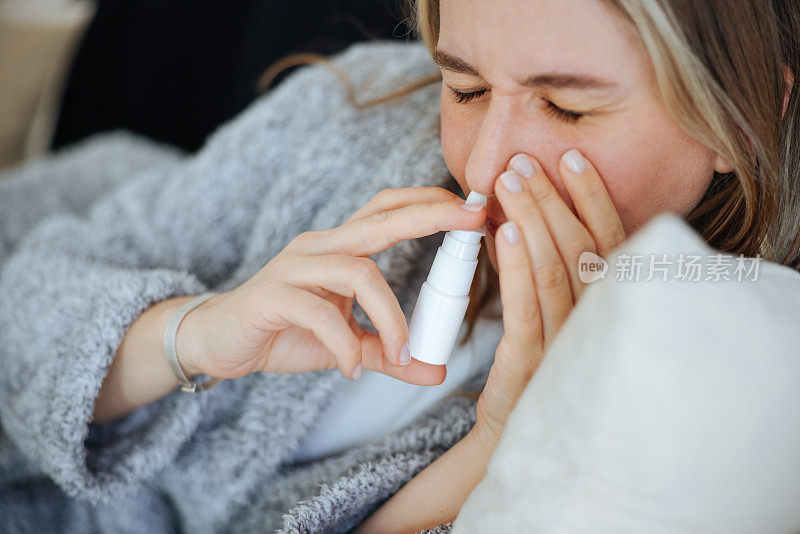生病的年轻女子使用鼻腔喷雾剂