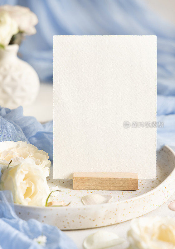 卡片附近的浅蓝色薄纱织物和奶油花在板上近距离，复制空间，婚礼模型