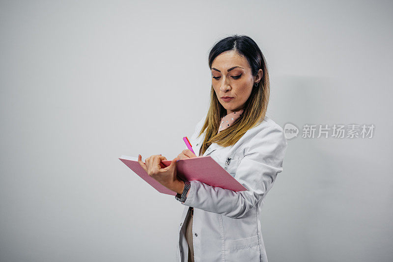 一位女性营养学家站在白色背景下写着笔记本