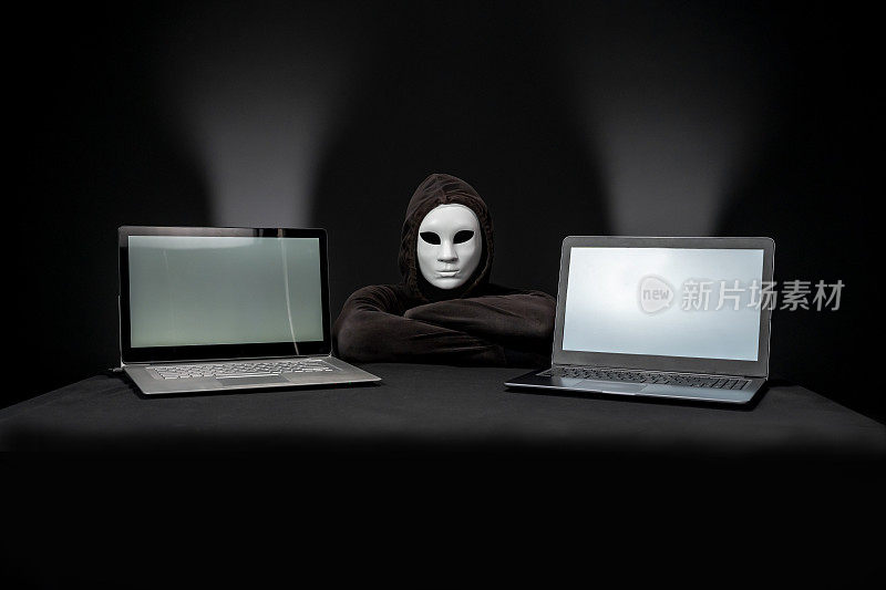 带着面具和两台笔记本电脑的黑客