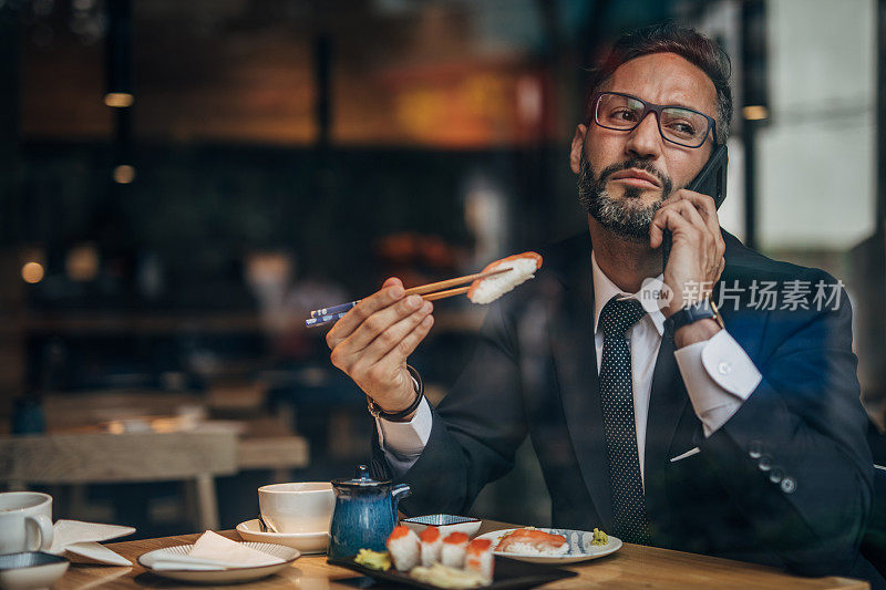 在寿司店打电话的男人