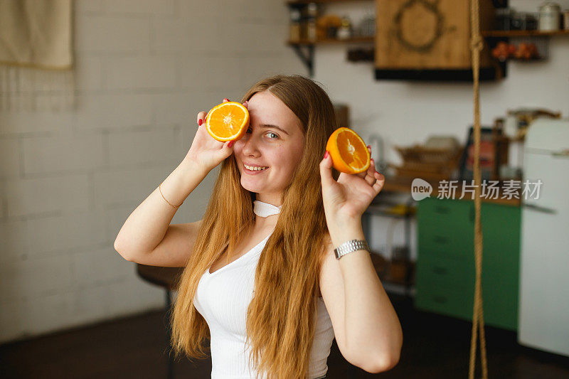 美丽的姜女孩拿着多汁的橘子。美丽快乐的少女拿着橘子片和大笑的情绪