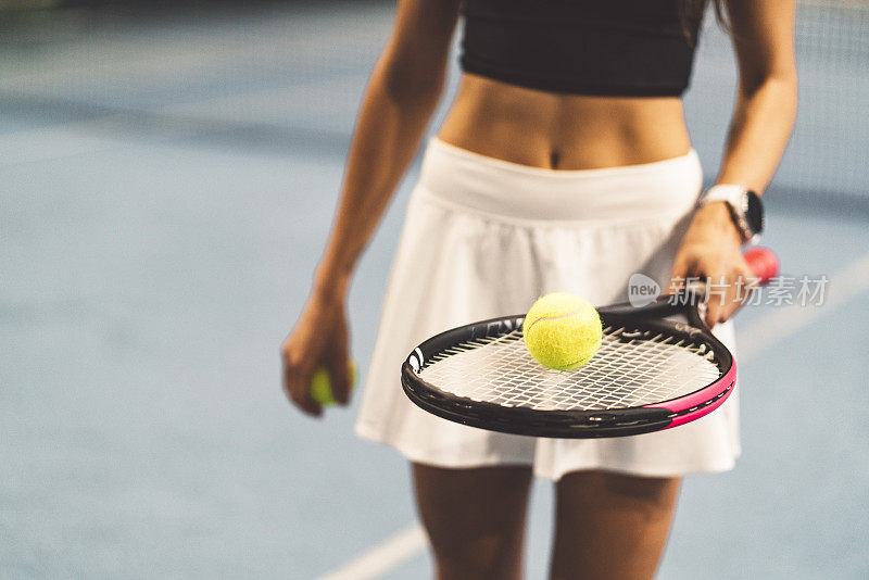 穿着网球服的女性，在网球拍上拿着一个网球