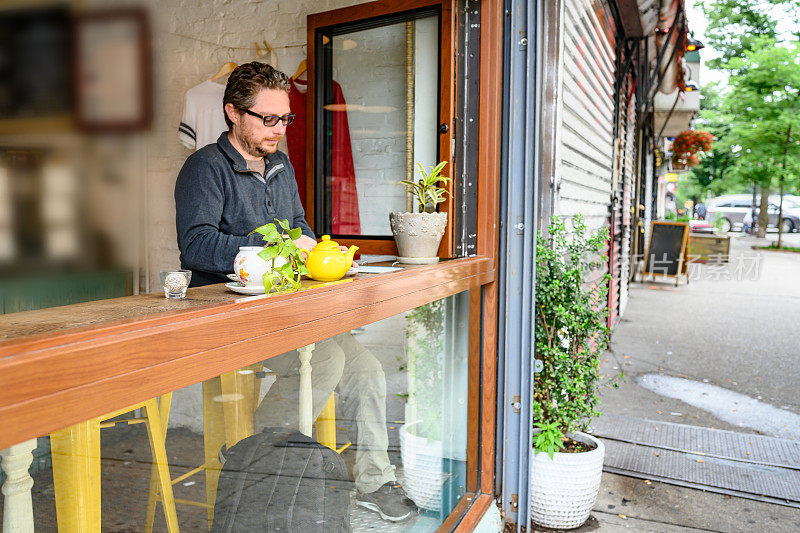 一个在布鲁克林咖啡馆靠窗座位喝茶的男人