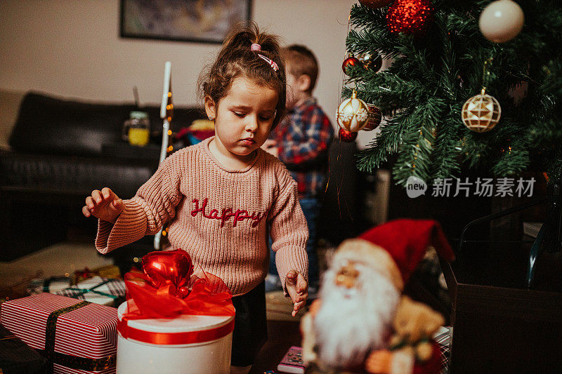 蹒跚学步的弟弟和妹妹在家里打开圣诞礼物